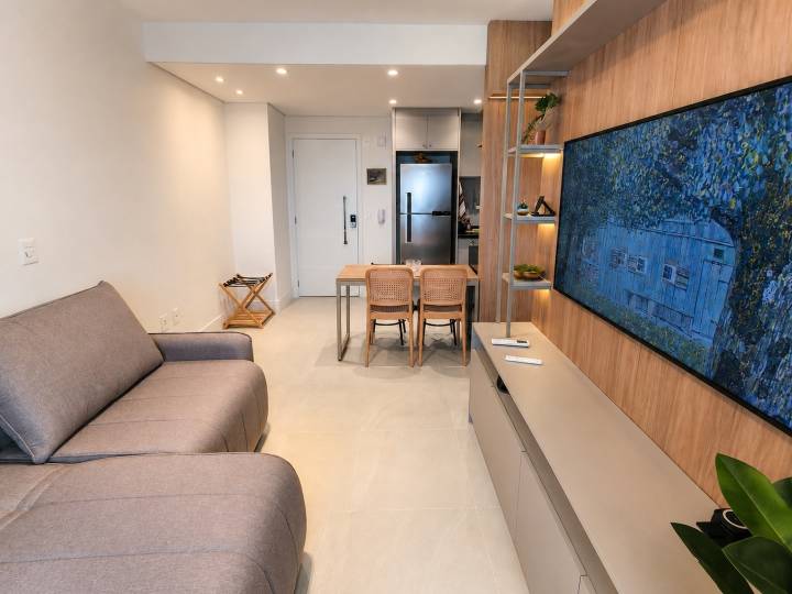 Sala mobiliada com sofá, jantar e cozinha integrada vista a partir da varanda