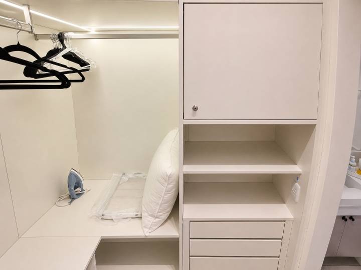 Marcenaria sob medida do closet com prateleiras, gavetas e cabideiros iluminados