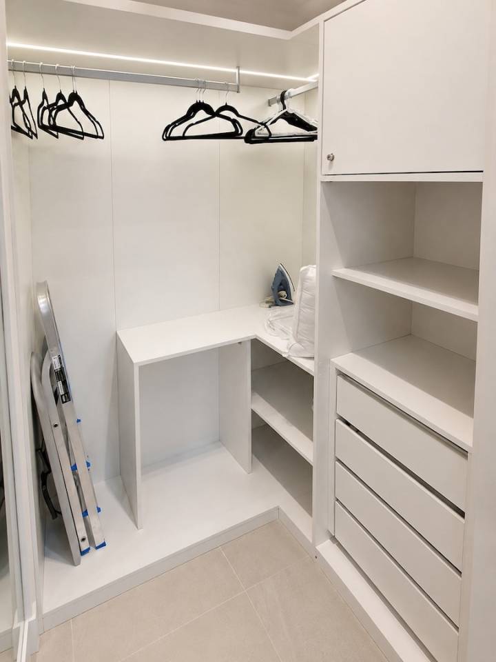 Closet planejado com cabideiros, gavetas, nichos e iluminação integrada