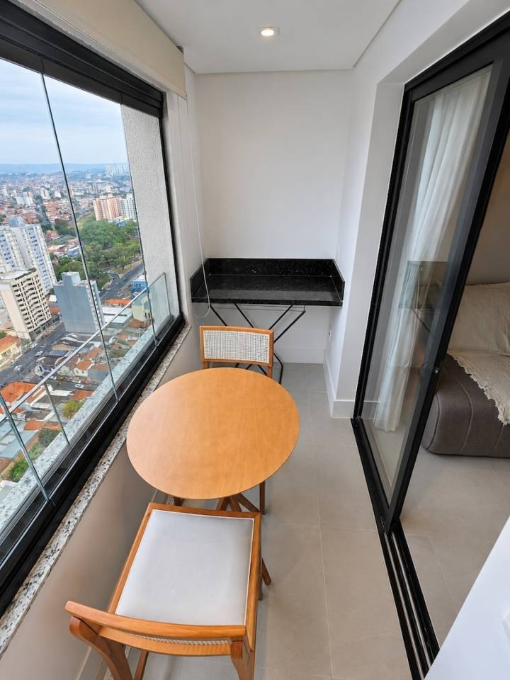 Varanda envidraçada do Sirius Patriani com mesa, bancada e vista de Campinas em andar alto