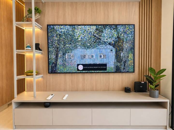 Painel amadeirado da sala com TV Samsung The Frame, nichos e iluminação em LED