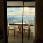 Varanda envidraçada com mesa para duas pessoas e vista panorâmica de Campinas a partir da sala